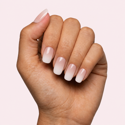 Nude and white ombre baby boomer gel nail strips worn on a tan olive skin tone hand