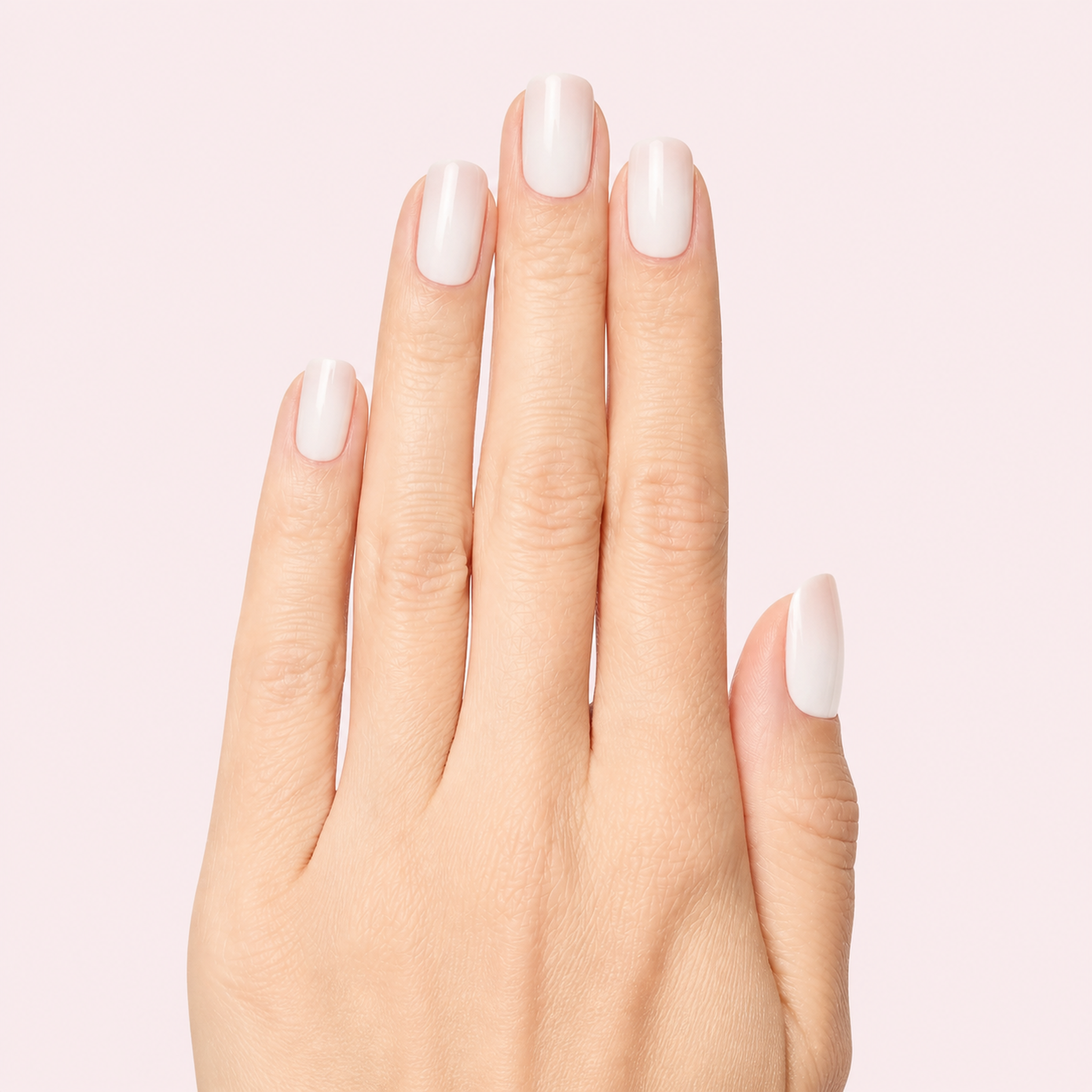 Nude and white ombre baby boomer gel nail strips worn on a light skin tone hand