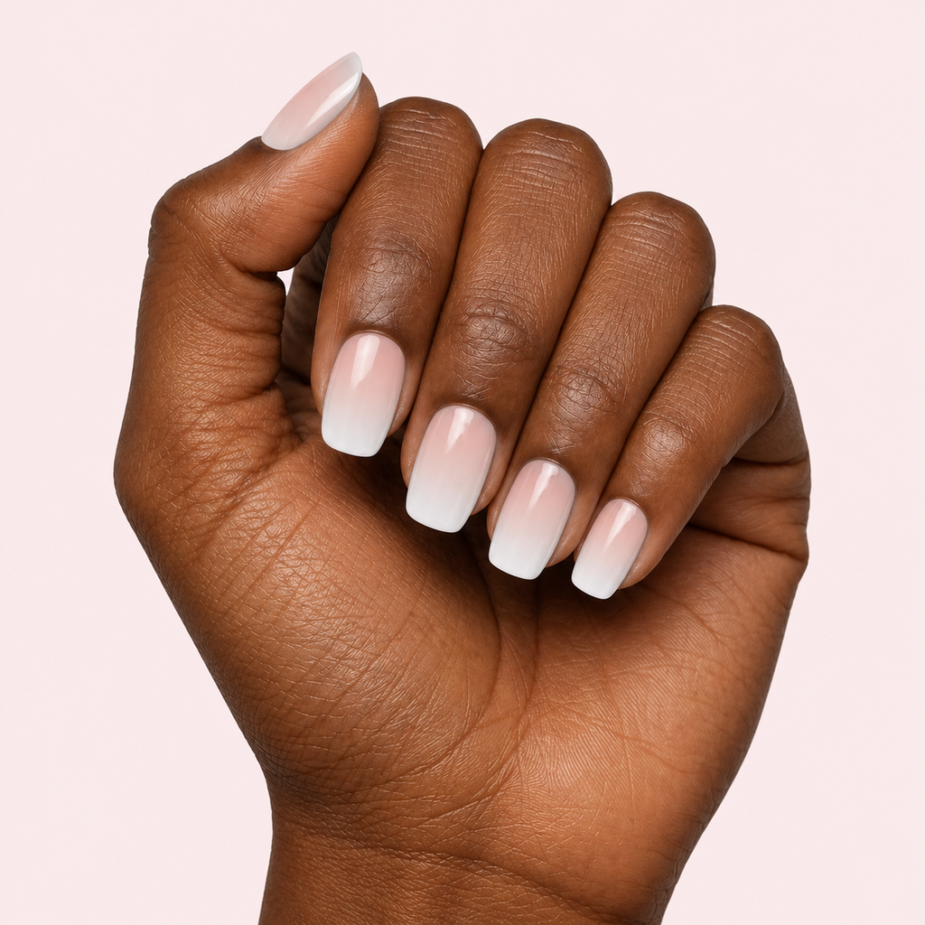 Nude and white ombre baby boomer gel nail strips worn on a deep skin tone hand