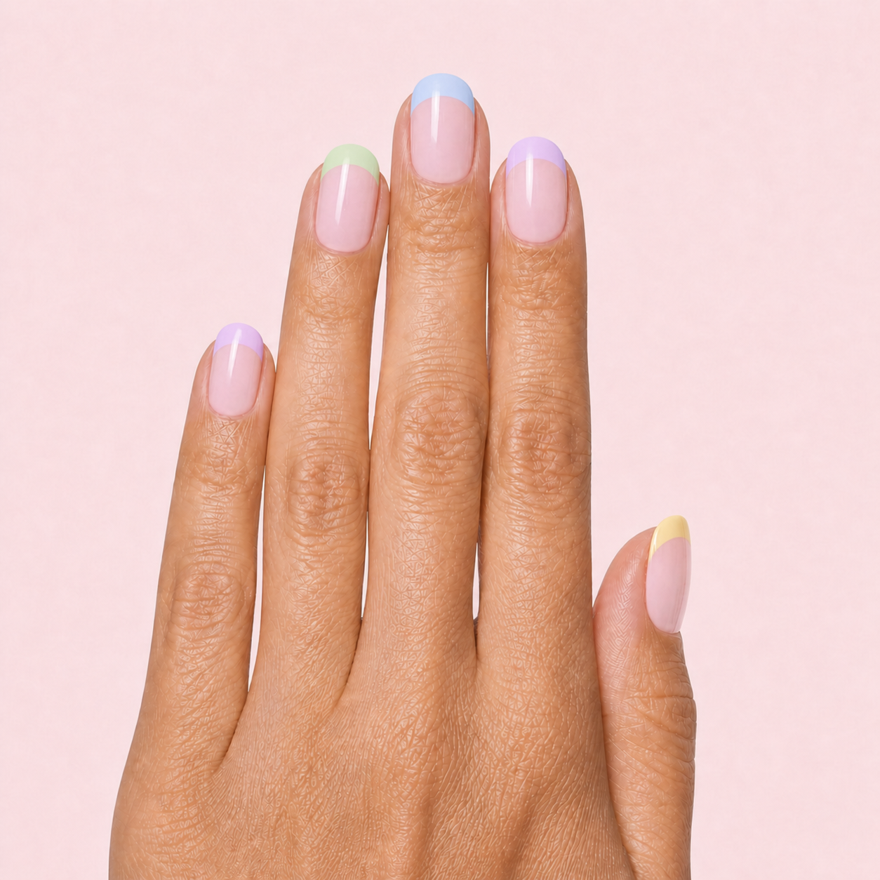 Pastel multicolor French tip gel nail strips worn on a tan olive skin tone hand