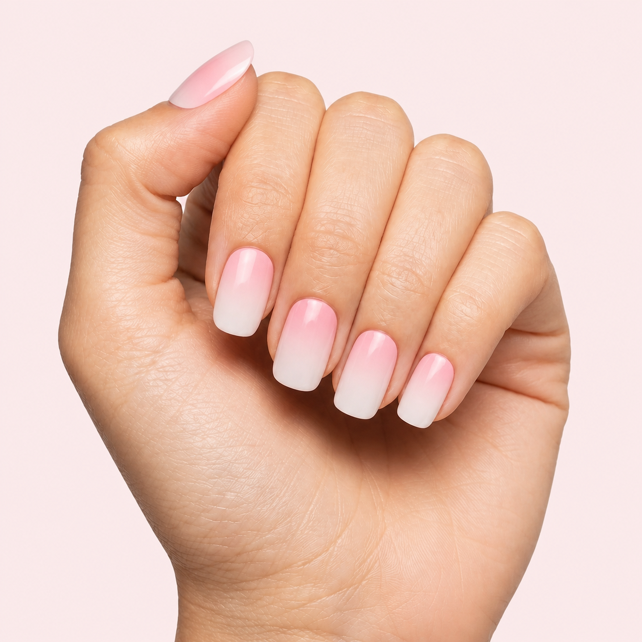 Pink and white ombre baby boomer gel nail strips worn on a light skin tone hand