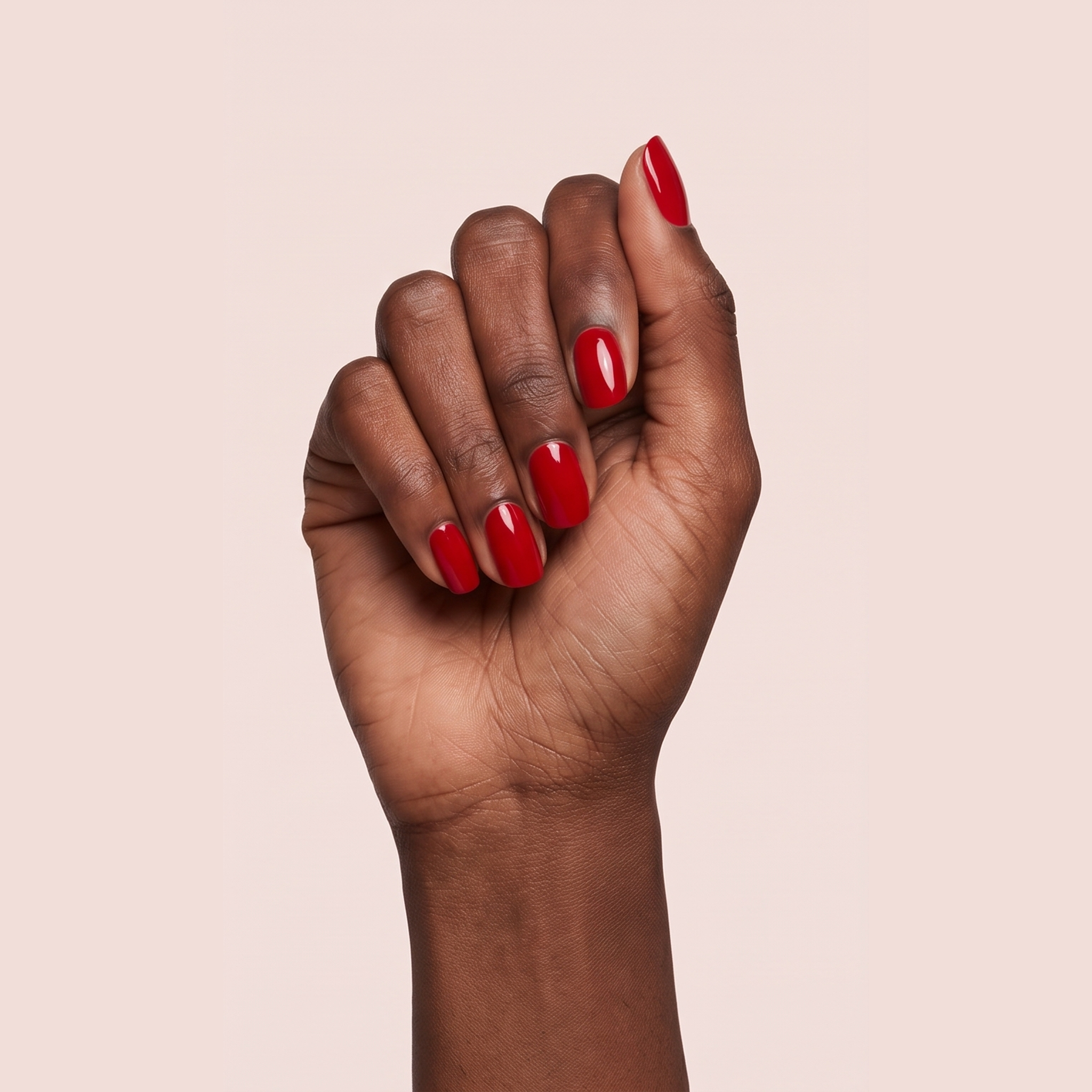 Classic warm red gel nail strips worn on a deep skin tone hand