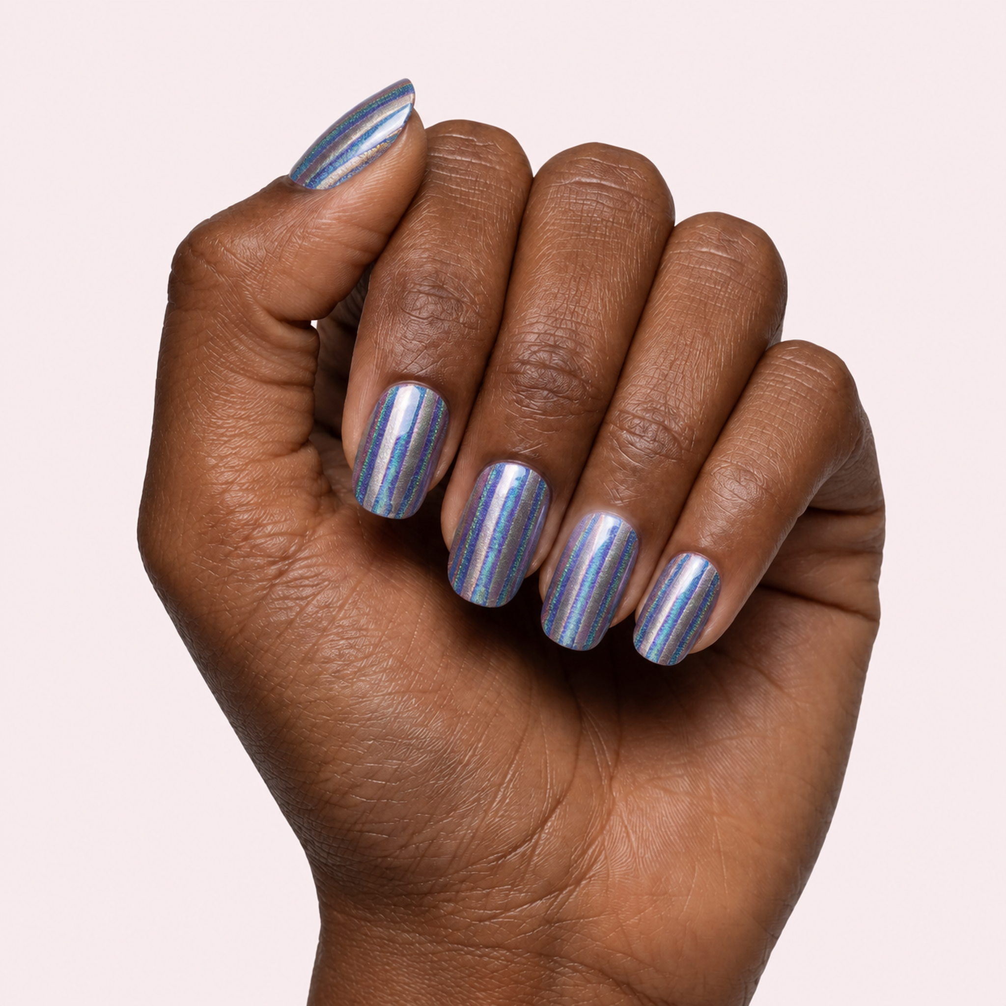Blue grey gel nail strips with gold vertical stripes worn on a deep skin tone hand