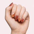 Terracotta and gold marble gel nail strips worn on a light skin tone hand