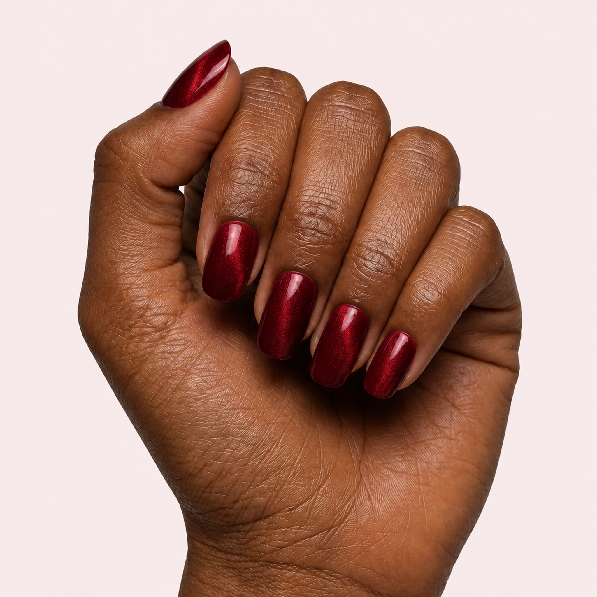 Burgundy chrome metallic gel nail strips worn on a deep skin tone hand