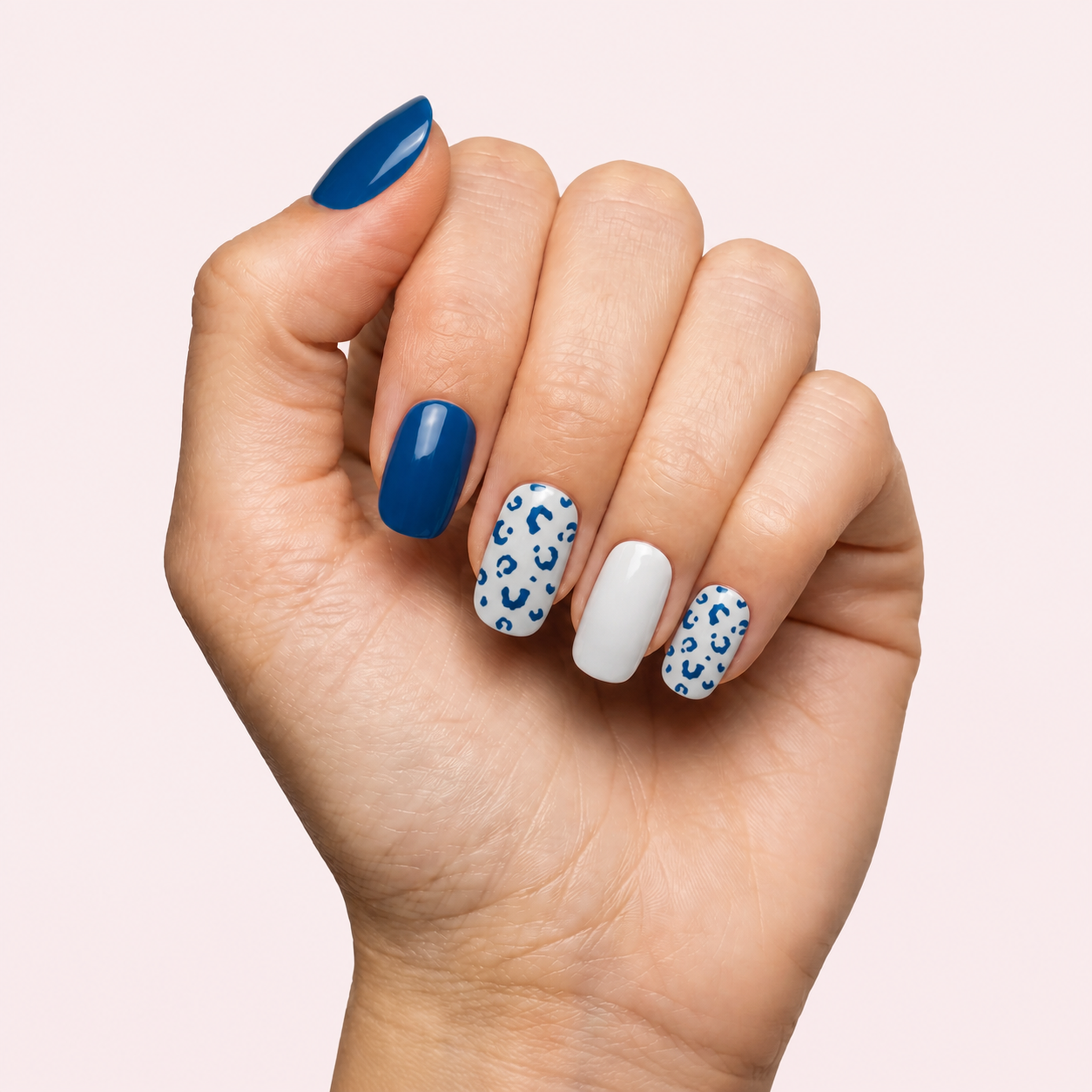 Navy blue and white leopard print gel nail strips worn on a light skin tone hand