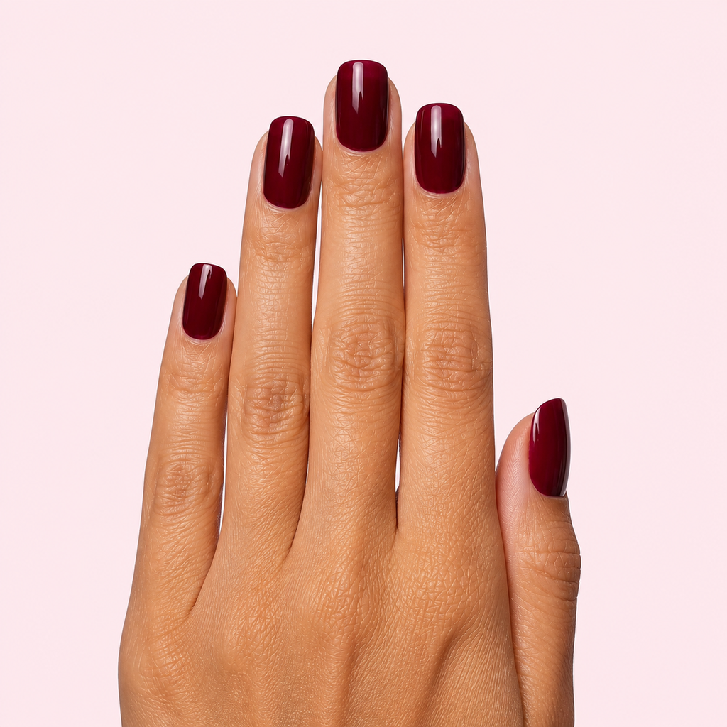 Dark cherry red glossy gel nail strips worn on a tan olive skin tone hand