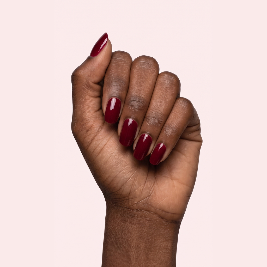 Dark cherry red glossy gel nail strips worn on a deep skin tone hand