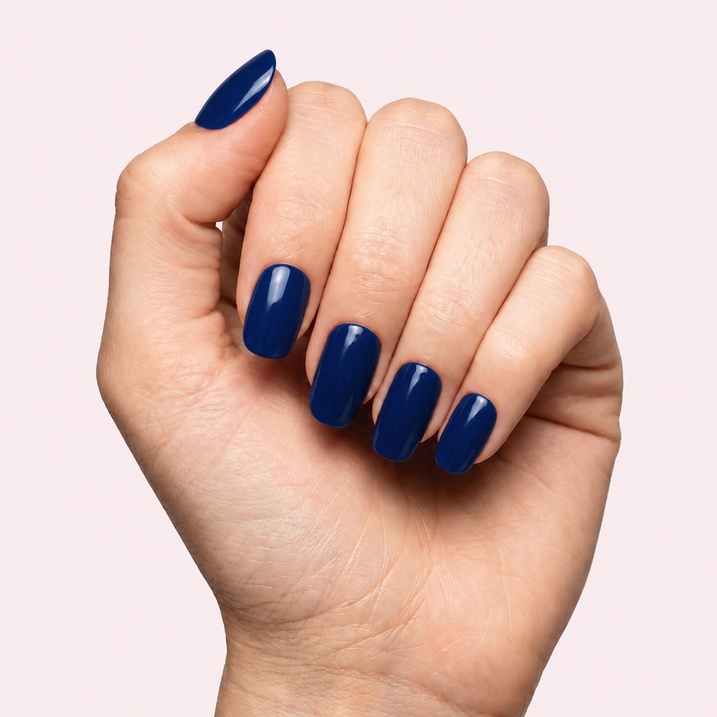 Navy blue glossy gel nail strips worn on a light skin tone hand