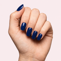 Navy blue glossy gel nail strips worn on a light skin tone hand