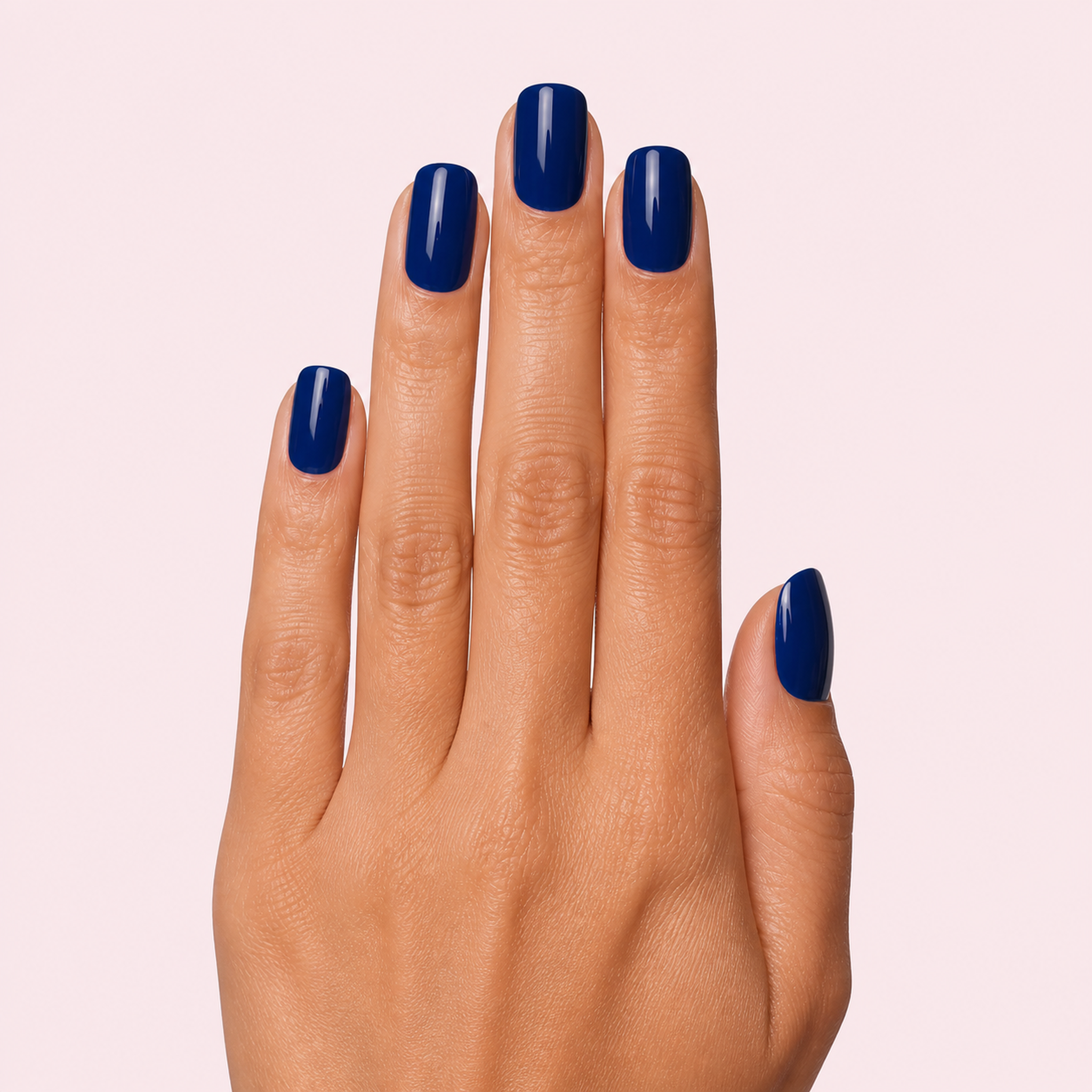 Navy blue glossy gel nail strips worn on a tan olive skin tone hand