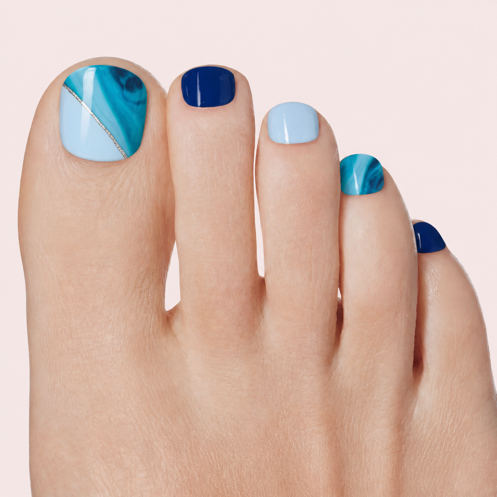 Blue marble mix gel toenail strips with navy and silver detail worn on a light skin tone foot